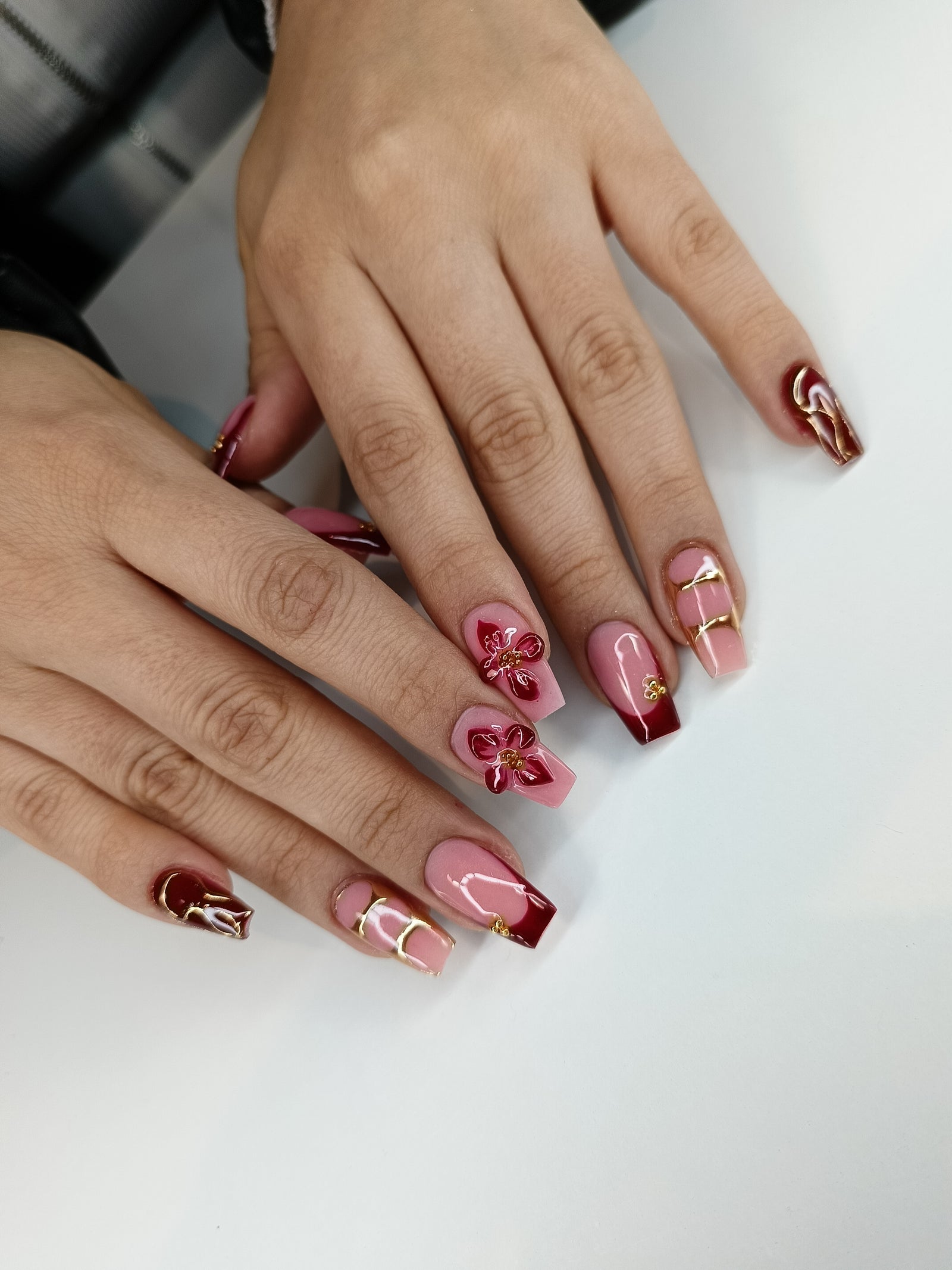 Vierkante nagels in nude en bordeaux met een bloem
